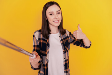 Photo of reliable lady hold selfie stick shoot portrait raise thumb up isolated yellow color background
