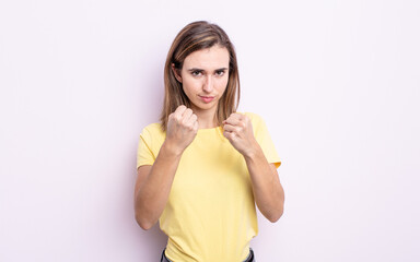 young pretty girl looking confident, angry, strong and aggressive, with fists ready to fight in...