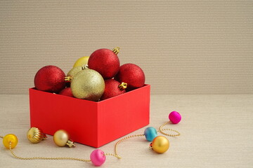 New year red and gold balls in a red box for decoration. Christmas winter concept. Side view, copy space.