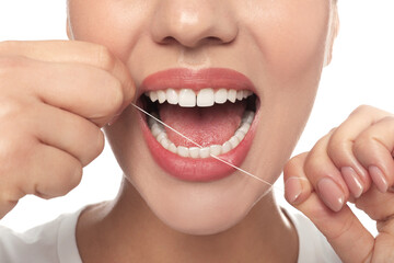 Woman flossing his teeth on white background, closeup. Dental care