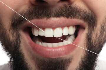 Man flossing his teeth on white background, closeup. Dental care