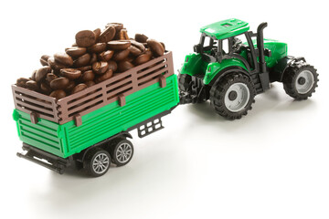 Toy tractor with a cargo trailer transports a variety of roasted coffee beans. The concept of agricultural work, harvesting, preparation for sale and delivery. Selective focusing