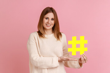 Hashtag and blogging. Portrait of attractive happy blond woman holding big paper hash symbol and...