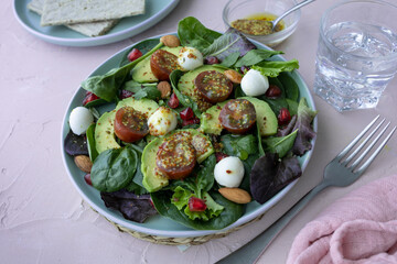 Green leafy salad with avocado, pomegranate, mozzarella balls, cherry tomatoes and almonds. Healthy food. Homemade food