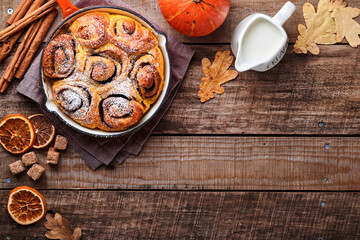 Cinnabon cinnamon rolls buns with pumpkin, nut, caramel and sugar cream iced on rustic wooden background table. Top view. Sweet Homemade Pastry christmas baking. Kanelbule - swedish dessert.