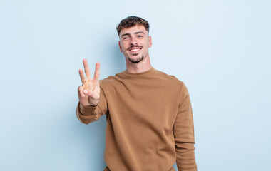 young handsome man smiling and looking friendly, showing number three or third with hand forward,...