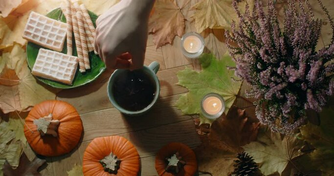Tabletop video of stiring tea with milk in slow motion. Decorated autumn composition in warm atmosphere with waffles, leaves and tea, 4k 60p Prores HQ