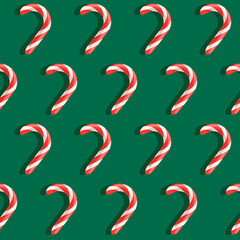 Seamless Christmas pattern with red and white candy canes on green background