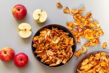 Homemade dried organic apple, sliced, in a plate, on a gray table background, top view, flat lay