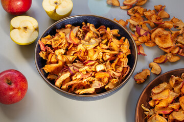 Homemade dried organic apple, sliced, in a plate, on a gray table background