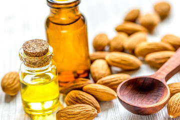 cosmetic and therapeutic almond oil on light wooden background