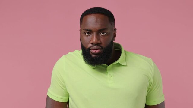 Confident vivid joyful satisfied fun young bearded african american man 20s wears green t-shirtshaking dancing fooling around with head isolated on plain pastel light pink background studio portrait