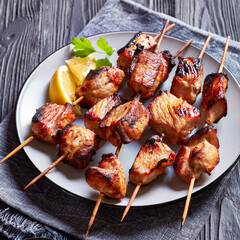 Juicy grilled pork kebabs on a plate with lemon wedges and ketchup, horizontal view from above