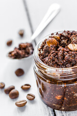 Homemade cosmetics with scrub and coffee beans on desk background