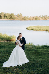 the groom and the bride are walking in the forest near a narrow river