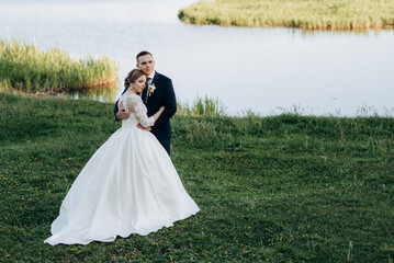 the groom and the bride are walking in the forest near a narrow river