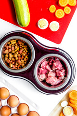 food for pets with meat and eggs on kitchen background top view