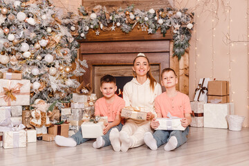 Obraz na płótnie Canvas smiling woman and two boys sitting on the floor near the Christmas tree