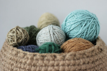 Fototapeta na wymiar Skeins of colored yarn in a jute basket on a white background