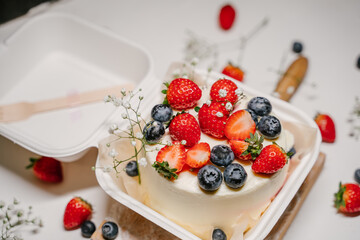 Beautiful white cake decorated with strawberries, blueberries and flowers