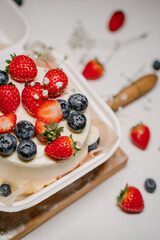 Beautiful white cake decorated with strawberries, blueberries and flowers