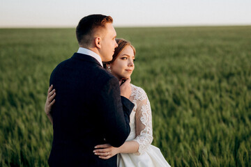 the groom and the bride walk along the wheat green field