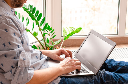 Close Up Low Angle View Of A Man Working From Home On A Laptop Computer Sitting At A Desk Surfing The Internet