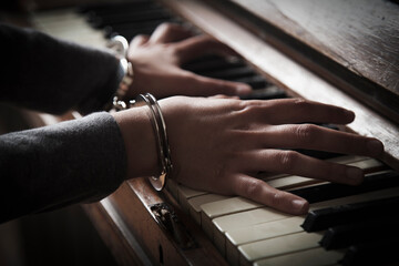 Conceptual image:music is my life. Handcuffed woman playing piano.