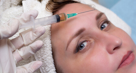 Middle-aged woman, 40+ on facial treatments. Botox injections. Anti-aging treatments. Face close-up. Copyspase.