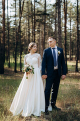 the bride and groom are walking in a pine forest