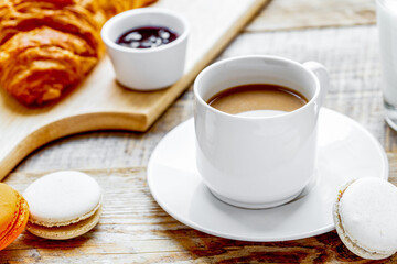 sweet breakfast with coffee, macaroons and croissants on wooden table