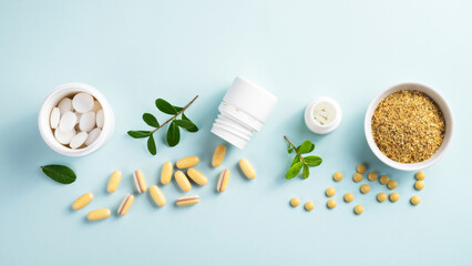 Vitamins and herbal supplements in jars with a green plant on a blue background..Biologically...