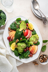 Healthy salad with red apple, wallnuts, grapes and fresh spinach leaves. Bright background