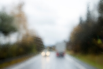 Driving with no windscreen wipers in heavy rain with oncoming traffic. Unwiped rain water off a windshield. Limited visibility due to weather