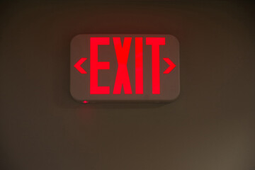 Illuminated EXIT sign on the wall of a dark hallway
