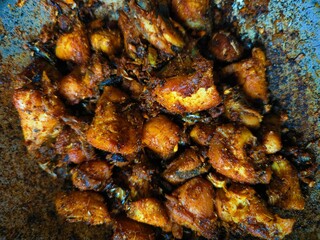 Fried chicken pieces in a bowl with oil indian style, added chilli powder