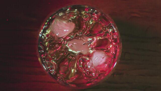 Slow motion of falling ice cube into whiskey glass