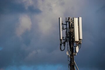 Electromagnetic radiation. Telecommunication tower with 5G and 4G antennas among clouds (with copy space)