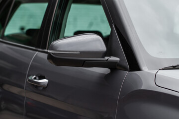 Close up front view of car side mirror. Front rear view mirror on the car window. Car exterior details. Gray car mirror.