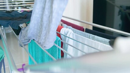 Drying rack with towels and clothes, person hanging clothes to dry