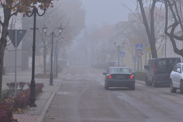 Obraz premium Autumn street, car, street lamp and fog on a gloomy day. Autumn.
