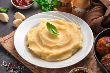 Mashed potatoes in a white plate with basil close-up.