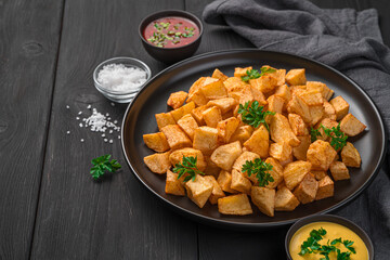 Patatas bravas with sauces on a black background. Spanish appetizer.