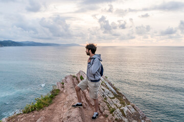 Obraz premium Horizontal view of adventurous traveler man sightseeing in Zumaia cliffs. Horizontal panoramic view of man traveling in vasque country. People and travel destination in Spain