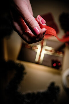 Close up picture of beautiful woman hands holding a red ribbon for wrapping Christmas gift
