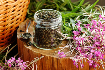 Willow herb tea, fermented herbal dry tea in glass jar with fresh flowers close on wooden rustic background, traditional russian hot drink, closeup, naturopathy and natural medicine concept - obrazy, fototapety, plakaty