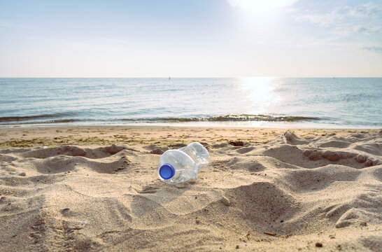 An empty, discarded plastic bottle on a sandy beach