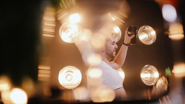 Barman juggling bottle with the blurred glasses on foreground. Bartender flaring show