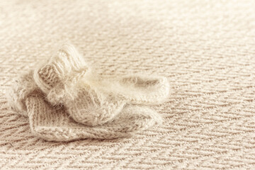 Fototapeta na wymiar Warm Woolen knitted children`s socks on beige textured knitted background. Warm handmade knitwear. Top view