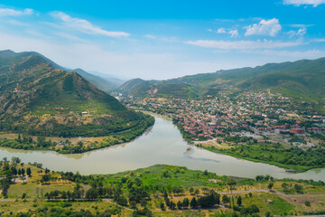 Fototapeta na wymiar The top view of Mtskheta, Georgia. The historical town lies at the confluence of the rivers Mtkvari and Aragvi. Georgian landscape with blue sky above